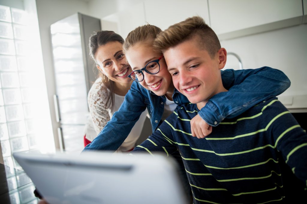 Family in kitchen surrounding computer